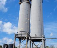 Two industrial silos under blue sky.