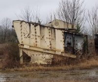 Rusty abandoned machinery in overgrown field.