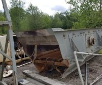 Rusty industrial machinery outdoors near trees.