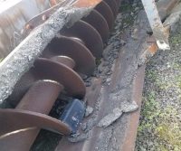 Rusty auger machine with concrete debris.