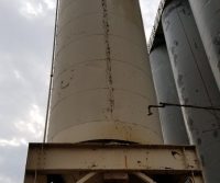 Large industrial silo under cloudy sky.