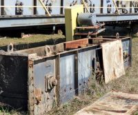 Rusty industrial equipment on grassy ground.