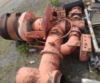 Rusty industrial machinery with pipes on ground.
