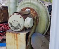 Old industrial fan under wooden shelter.